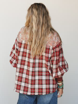 Shot from behind, this mixed-print flannel top pairs a red plaid body with a floral yoke panel — the kind of top that looks like it's been in someone's closet for years in the best way, styled with stacked turquoise bracelets and wide-leg denim.