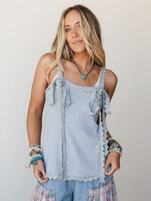 A relaxed lace-trimmed cami tank in heather gray is styled with a tiered floral skirt and stacked boho bracelets — the kind of effortless layered look that feels personal, not planned.