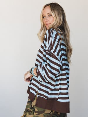 A relaxed striped knit top in mocha and sky blue gets an unexpected edge paired with camo cargo pants — the kind of mix that looks effortless but is clearly intentional.
