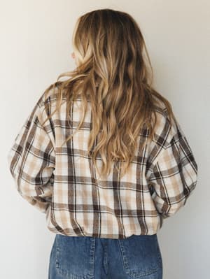 Shot from behind, a model in a cropped plaid flannel top and denim jeans faces away from camera — the kind of effortless, lived-in look that makes you want to grab coffee and wander a farmer's market.
