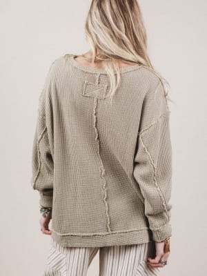Person wearing a beige textured sweater with a plain background
