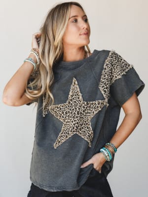 A washed charcoal graphic tee with a frayed leopard print star patch and studded detail steals the show, styled with stacks of turquoise and beaded bracelets for that effortlessly cool, lived-in energy.