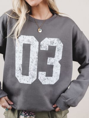Person wearing a gray sweatshirt with the number 03 printed on it.