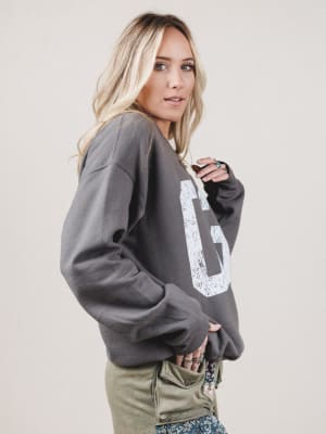 Woman wearing a gray sweatshirt with a logo on a plain background
