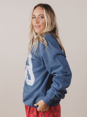 Woman wearing a blue hoodie with a white logo on a plain background