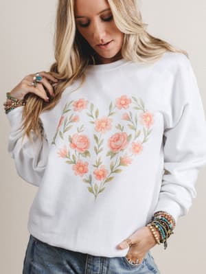 Woman wearing a white sweatshirt with floral design on a beige background