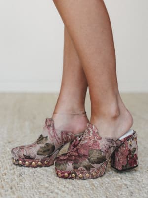 A close-up of tapestry platform clogs in a faded floral print — the kind of shoes that make a whole outfit feel like it was meant to be.