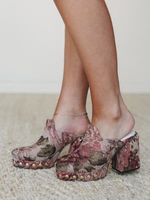 A close-up of tapestry platform clogs in a faded floral print — the kind of shoes that make a whole outfit feel like it was meant to be.