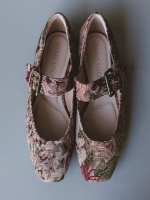 Pair of floral-patterned shoes with a buckle on a gray background