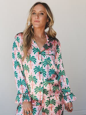 A satin pajama set in a bold palm tree and flamingo print — the kind of set that makes staying in feel just as intentional as going out.