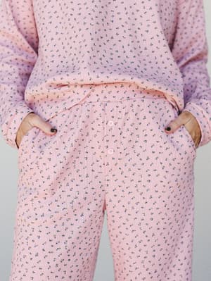 A close-up of a matching floral set in soft pink — the ribbed texture and tiny ditsy florals give it that cozy, lived-in feel, with the button-fly pants detail doing a lot of quiet charm work.