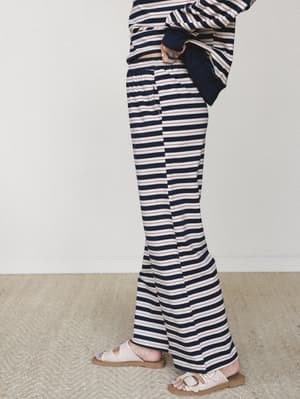 A side-angle shot of wide-leg striped sweatpants paired with a matching striped top and neutral buckle sandals — relaxed and effortless with a subtle nautical pull.