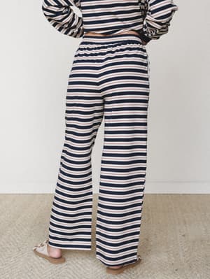 Shot from behind, a model wears wide-leg striped sweatpants paired with a matching striped long-sleeve top — a nautical-leaning co-ord set that feels effortlessly relaxed and just put-together enough.