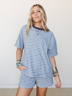 A relaxed blue and white stripe matching set — oversized tee and mini shorts — styled with stacked turquoise bracelets and layered gold necklaces for that effortless, lived-in summer feel.
