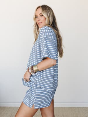 A matching striped two-piece set in soft periwinkle blue and cream — the kind of effortless outfit that looks like you tried just enough, styled with a stack of boho bracelets and a glance over the shoulder.