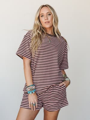 A matching striped tee-and-shorts set in dusty pink and dark brown worn with stacked turquoise and beaded bracelets — the kind of effortless two-piece that looks intentional without trying.