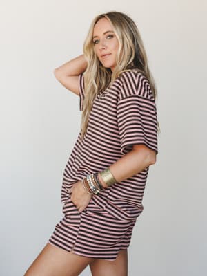 A relaxed striped mini dress or oversized tee worn as a dress, styled with stacked bracelets and a gold cuff — the kind of effortless outfit that looks like you tried just the right amount.