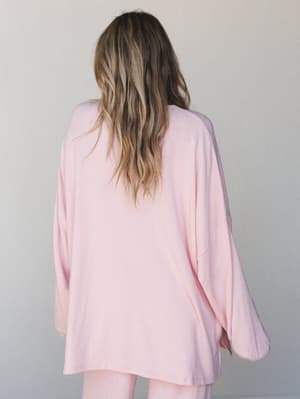Shot from behind, a model in a oversized blush pink long sleeve top with wide, relaxed sleeves — soft, unhurried, and the kind of thing you'd reach for on a slow morning.