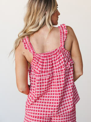 A close back-view shot of a red gingham top with tiny heart print details, ruffle-trimmed straps, and a relaxed tiered silhouette — sweet and summery with a little vintage charm.