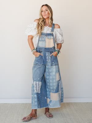 A wide-leg denim patchwork overall styled over a flowy off-shoulder blouse, layered with turquoise beaded jewelry — the kind of outfit that somehow looks intentional and effortless at the same time.