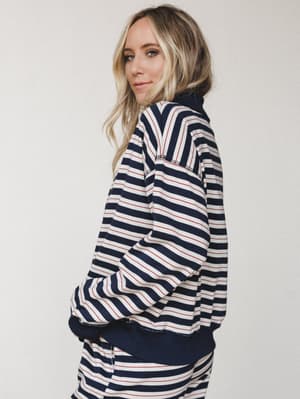 A model shot from the side in a navy striped sweatshirt with a cozy, relaxed feel — the nautical stripe and oversized silhouette give it that effortless, thrown-on-and-going energy.