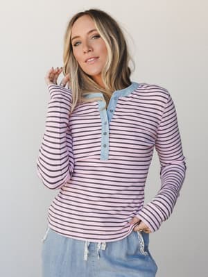A striped ribbed henley top in blush pink and dark cocoa with a chambray button placket and collar detail, styled with soft blue drawstring pants for an easy, put-together everyday look.