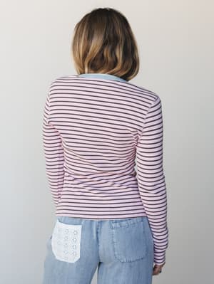 Shot from behind, this ribbed striped long-sleeve top in blush pink and dark cocoa pairs with light-wash jeans featuring a sweet eyelet lace pocket detail — the kind of back-of-the-outfit moment that makes people stop you on the way out.
