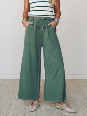Wide-leg drawstring pants in a washed army green paired with a striped textured top, woven flats, and stacked beaded bracelets — the kind of outfit that looks pulled-together without trying.