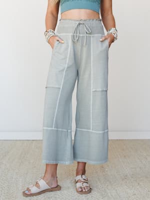 Wide-leg cropped pants in a washed sage tone styled with a teal crop top, beaded bracelets, and buckle sandals — easy, intentional, and made for the kind of day that doesn't have a schedule.