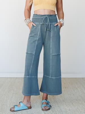 Wide-leg cropped lounge pants in a washed ash jade paired with a yellow crop top and light blue sandals — the kind of outfit that looks intentional but feels like staying in.