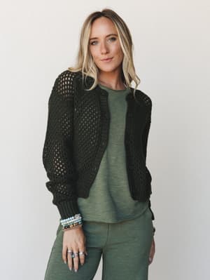 A tonal olive moment — open-knit dark olive cardigan layered over a sage tee and wide-leg pants, styled with stacked beaded bracelets and silver rings for that effortlessly collected, earthy feel.