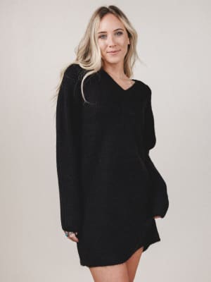 Woman wearing a black sweater dress against a plain background