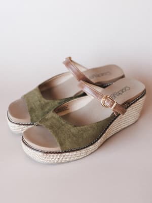 A pair of olive suede platform wedge sandals with a tan leather ankle strap and woven jute sole — the kind of shoe that makes even a farmer's market run feel intentional.