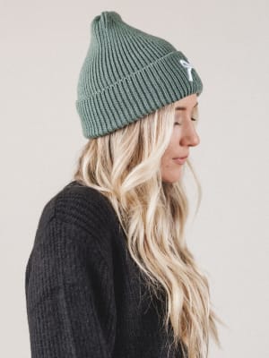 Person wearing a green beanie and dark sweater on a plain background