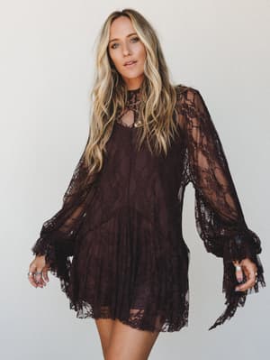 A deep chocolate lace mini dress with sheer bishop sleeves and tiered ruffled hem — the kind of piece that makes a Tuesday feel like it deserves more attention.