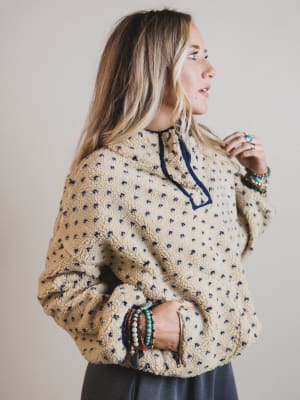 Woman wearing a patterned beige sweater with a neutral background