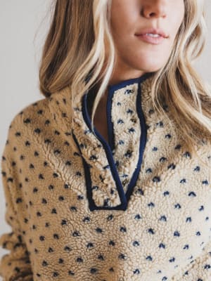 Close-up of a person wearing a patterned fleece sweater with a neutral background