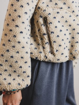 Close-up of a person wearing a textured beige sweater with a zipper, focusing on the fabric and zipper details.