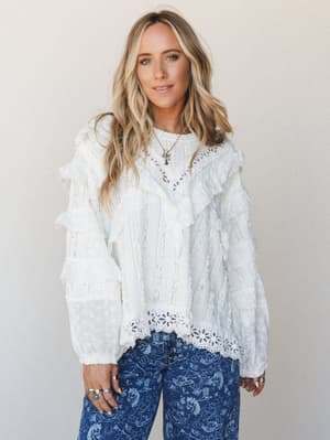 A lace and eyelet ruffle blouse in off white styled with printed denim — romantic and lived-in at the same time, the kind of top that makes everything in your closet feel more interesting.