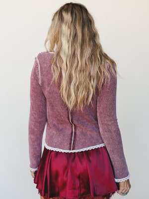 Shot from the back, this look pairs a fitted burgundy waffle-knit long-sleeve top with lace trim detailing against a satin mini skirt in deep crimson — effortlessly romantic and a little vintage, like something she's been wearing on repeat since she