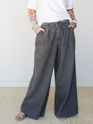 Acid-washed wide-leg trousers in a faded charcoal denim styled with a white tee, floral embroidered sleeves, and strappy sandals — relaxed and lived-in with an easy boho sensibility.
