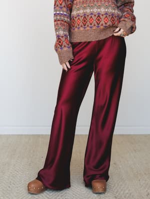 Silky wide-leg trousers in a deep mulberry paired with a cozy fair isle sweater and wood-platform clogs — the kind of outfit that feels like it figured itself out without trying.