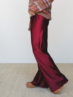 Silky wide-leg trousers in a deep mulberry paired with a multicolor fair isle sweater and wooden clogs — a fall outfit that feels both cozy and a little dressy at the same time.