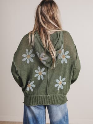 Person wearing a green hoodie with floral patterns on the back