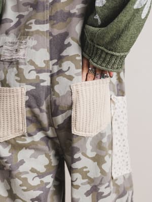 Camouflage jacket with woven pocket details on a neutral background