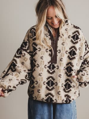 Woman wearing a patterned fleece jacket with a neutral background