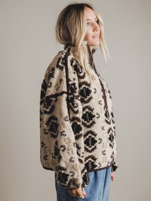 Woman wearing a patterned jacket against a plain background