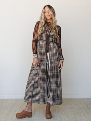 A tiered gingham maxi dress layered over a lace long-sleeve top comes together in the most effortlessly vintage-boho way — stacked bracelets, wood-soled clogs, and all.