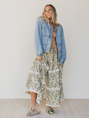 Woman wearing a denim jacket over a floral dress with a neutral background
