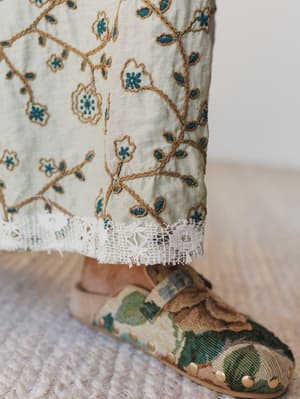 Embroidered fabric with floral patterns and a pair of embroidered shoes on a neutral background